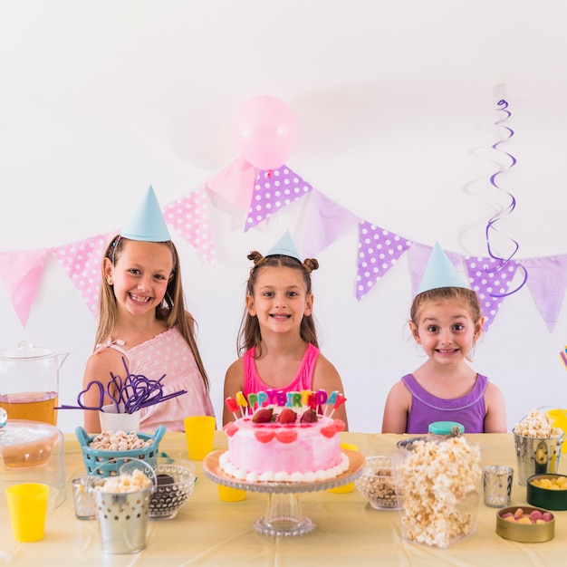 Retrato de niños sonrientes con sombrero de fiesta celebrando la fiesta de cumpleaños