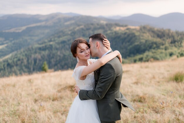 Retrato de un novio y una novia solos en las hermosas montañas en el soleado día de verano