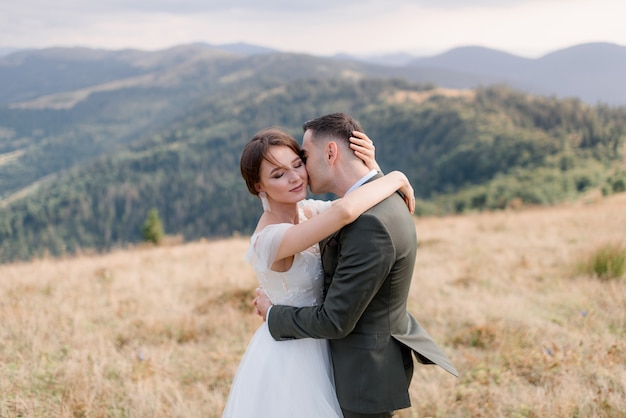 Retrato de un novio y una novia solos en las hermosas montañas en el soleado día de verano