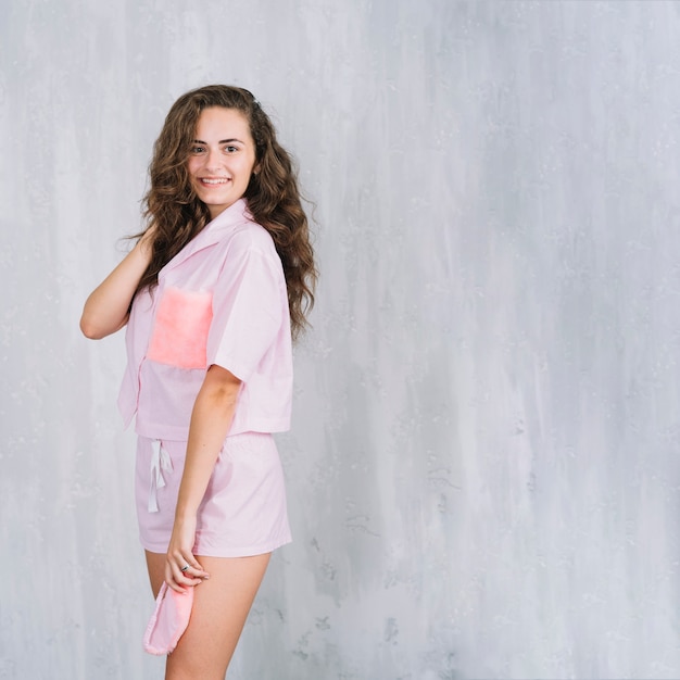 Retrato o una mujer joven sonriente de pie delante de la pared