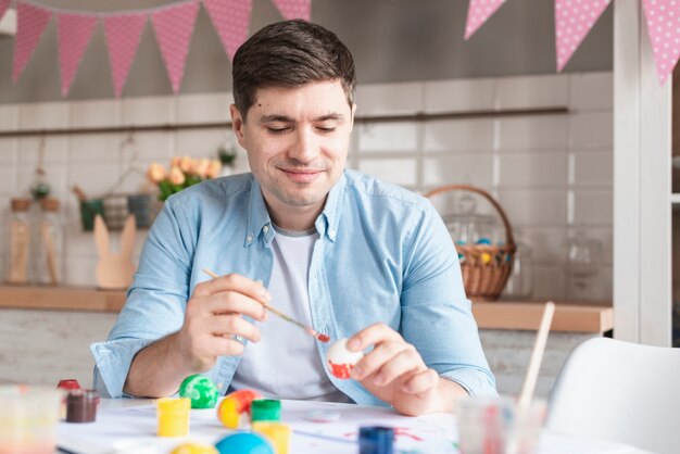 Retrato de padre positivo pintando huevos para pascua