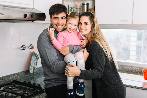 Retrato de padres felices con su hija en la cocina