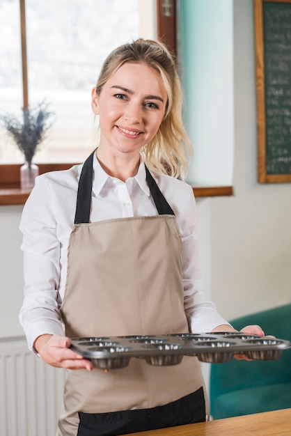 Retrato de un panadero de sexo femenino sonriente que sostiene moldes cocidos de los molletes