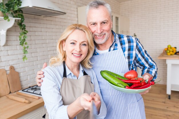 Retrato de un par mayor que se coloca en la cocina que toma el selfie en el teléfono móvil