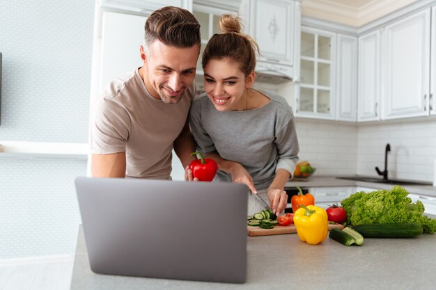 Retrato de una pareja amorosa alegre cocinar ensalada juntos