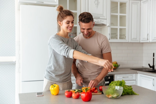 Foto gratuita retrato de una pareja amorosa alegre cocinar ensalada juntos