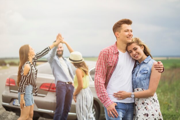 Retrato de la pareja amorosa frente a amigos dando alta cinco