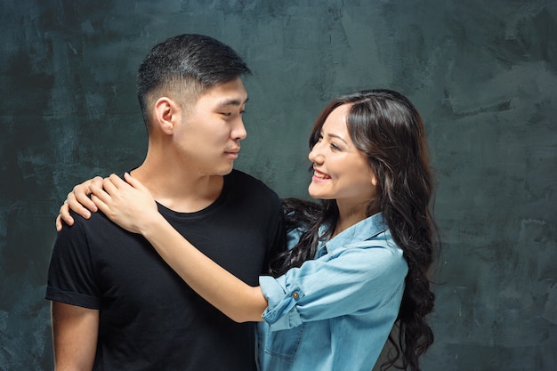 Retrato de pareja coreana sonriente en un estudio gris