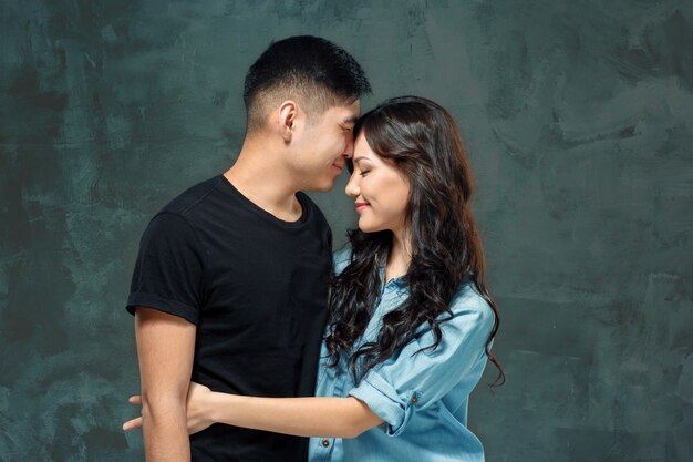 Retrato de pareja coreana sonriente en un estudio gris