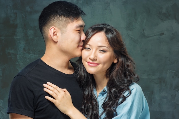 Retrato de pareja coreana sonriente en un estudio gris