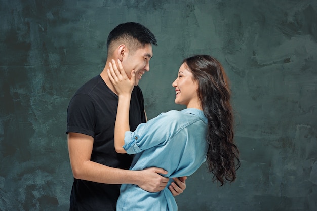 Retrato de pareja coreana sonriente en un estudio gris