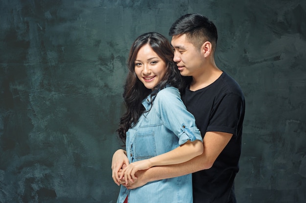 Retrato de pareja coreana sonriente en un estudio gris