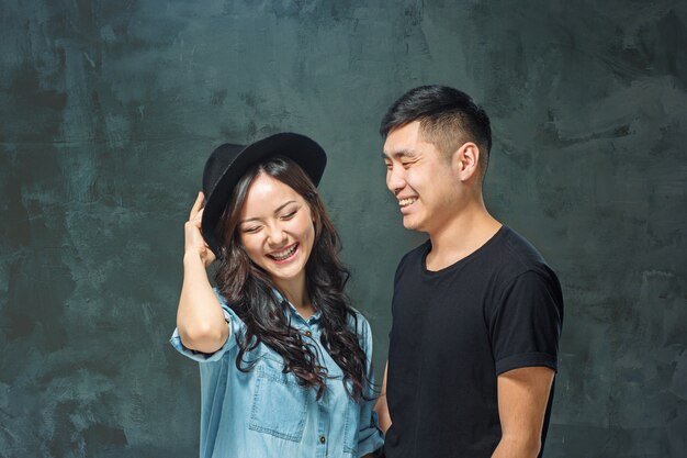 Retrato de pareja coreana sonriente en un estudio gris