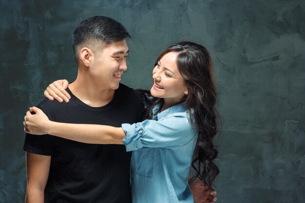 Retrato de pareja coreana sonriente sobre un fondo gris de estudio