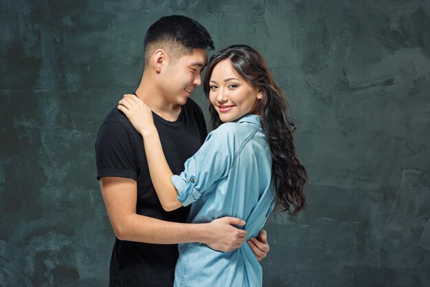 Retrato de pareja coreana sonriente sobre un fondo gris de estudio