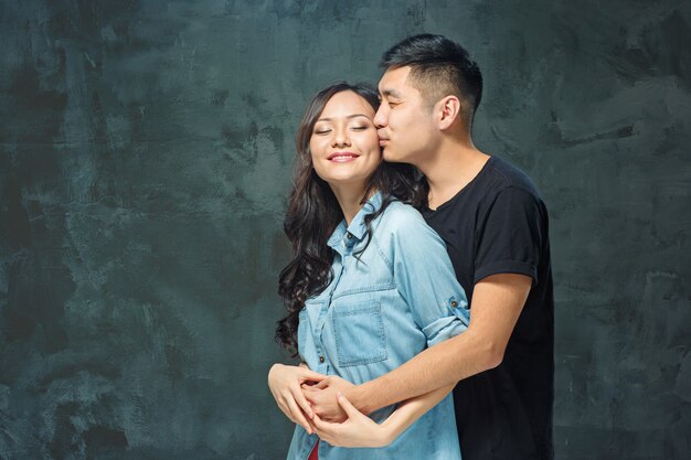 Retrato de pareja coreana sonriente sobre un fondo gris de estudio