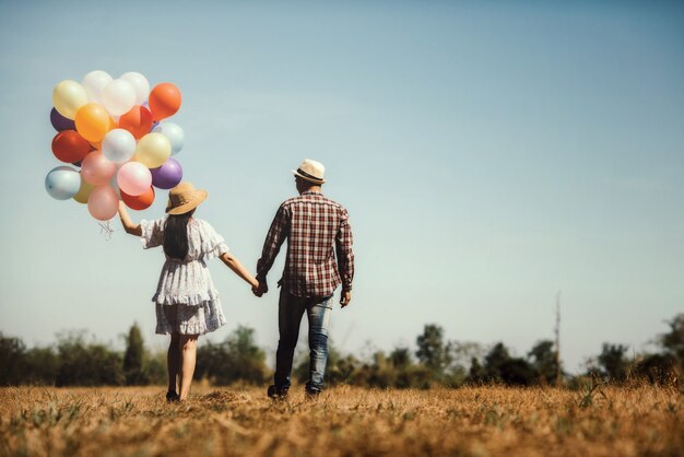 Retrato de una pareja enamorada caminando con globos de colores