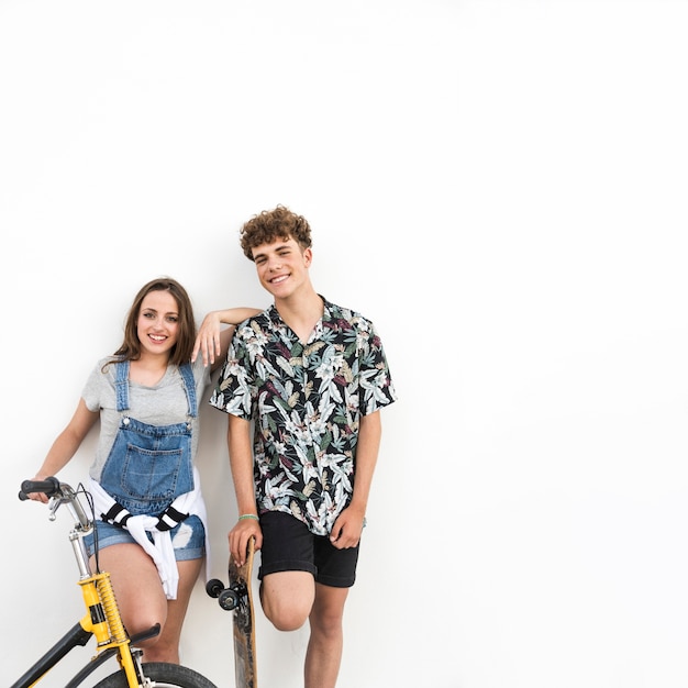 Retrato de una pareja feliz con bicicleta y patineta