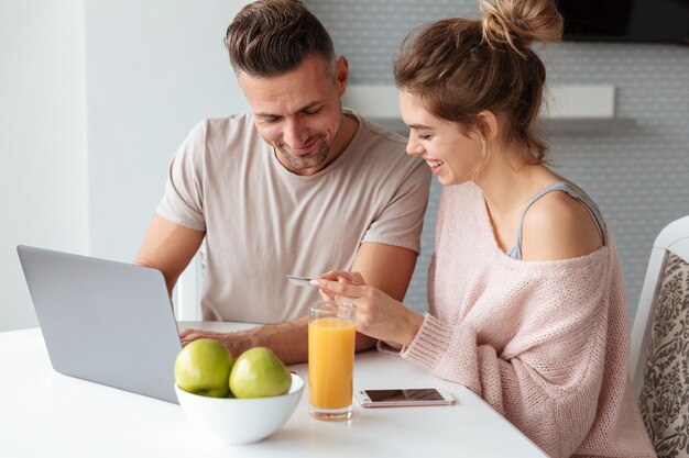 Retrato de una pareja feliz de compras en línea con laptop