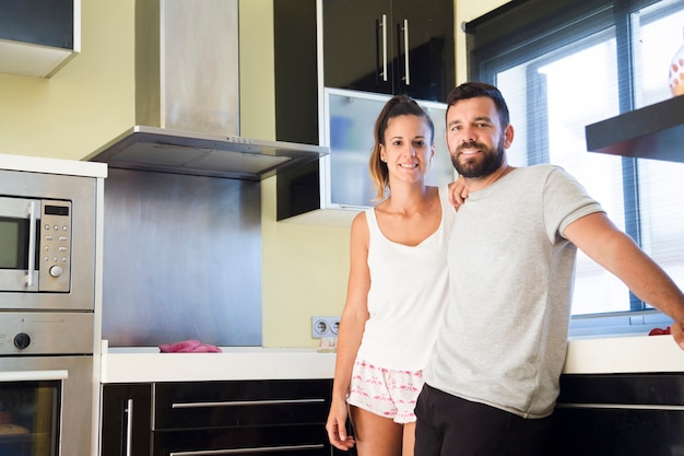 Retrato de una pareja feliz de pie en la cocina