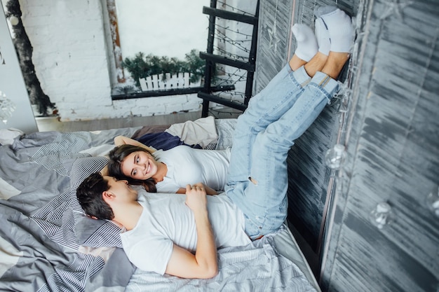 Retrato de pareja feliz relajándose en la cama y tomados de las manos y las piernas por la mañana