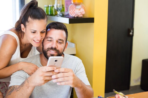 Retrato de una pareja feliz usando teléfono móvil