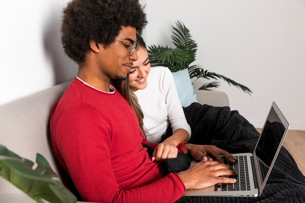 Retrato de pareja interracial usando portátil juntos