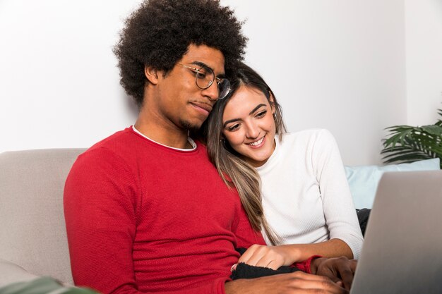Retrato de pareja interracial usando portátil juntos