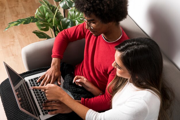 Retrato de pareja interracial usando portátil juntos