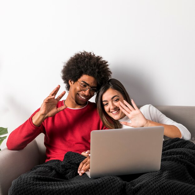 Retrato de pareja interracial usando portátil juntos