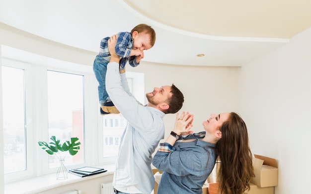 Foto gratuita un retrato de una pareja joven jugando con un bebé en un nuevo hogar