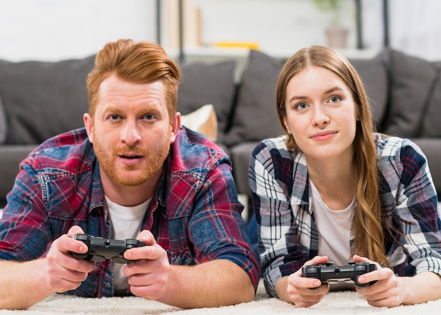 Retrato de pareja joven jugando con joystick en casa