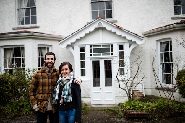 Retrato de pareja de pie cerca de una casa nueva