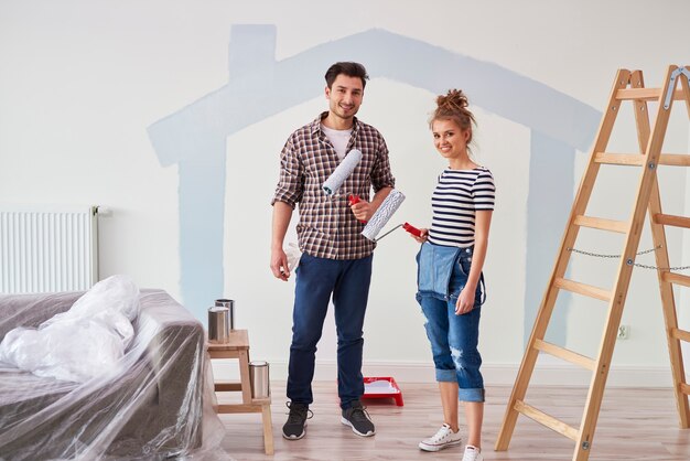 Retrato de pareja pintando la pared interior en apartamento nuevo