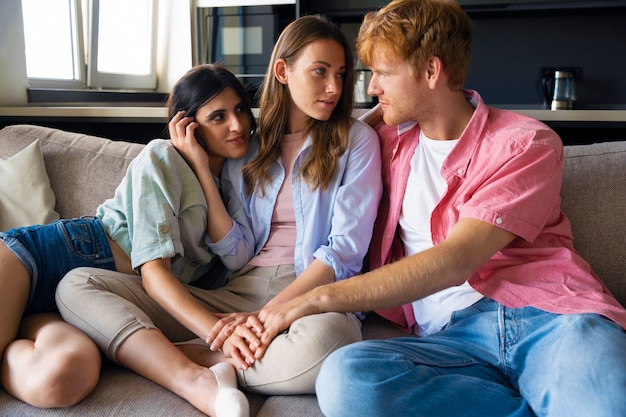 Foto gratuita retrato de pareja poliamorosa en casa sentada en el sofá juntos