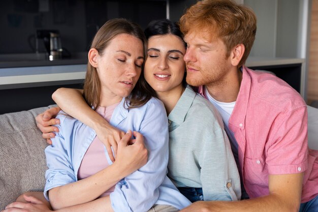 Retrato de pareja poliamorosa en casa sentada en el sofá juntos