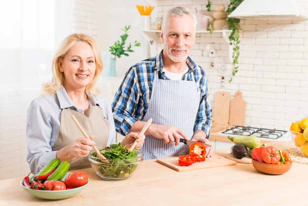 Foto gratuita retrato de una pareja senior preparando la ensalada en la cocina