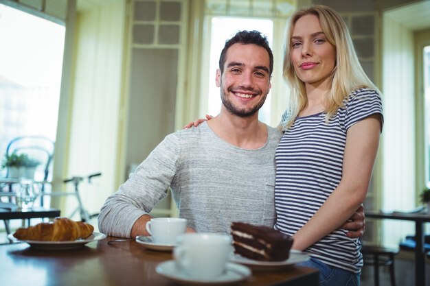 Retrato de pareja sonriente sentado con los brazos alrededor