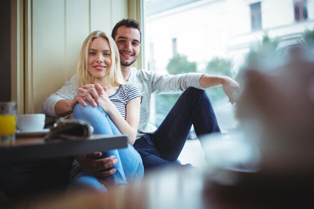 Retrato de pareja sonriente sentado con los brazos alrededor