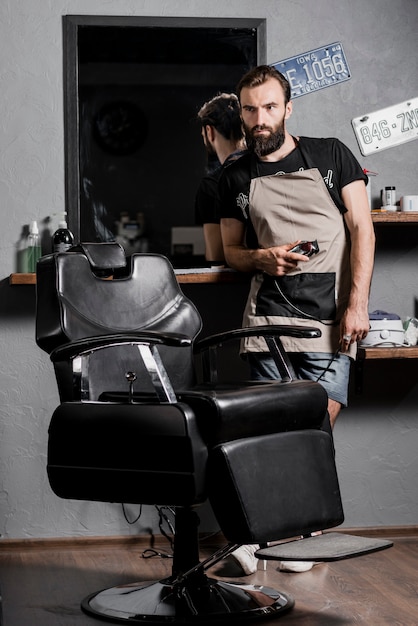 Retrato de un peluquero masculino con barba de pie en peluquería