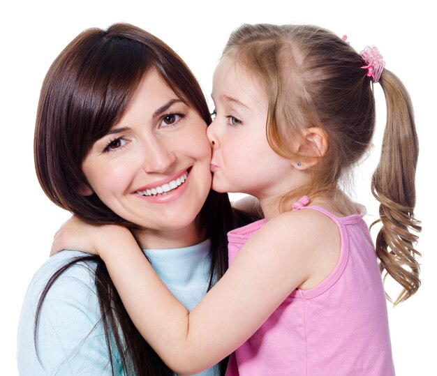 Retrato de pequeña hija besando a su hermosa madre feliz - aislada en blanco