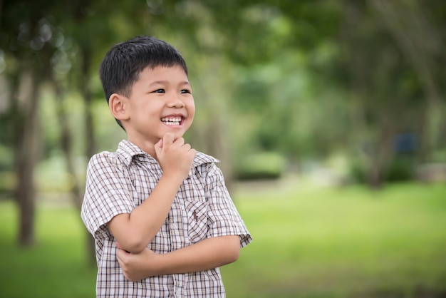 Retrato de la pequeña mano asiática linda del muchacho debajo de la barbilla y pensamiento mientras que se coloca