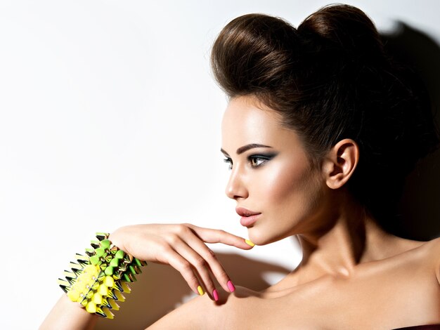 Retrato de perfil de una hermosa mujer con pulsera con espinas y uñas multicolores