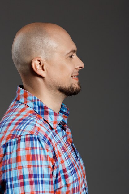 Retrato de perfil de hombre guapo confiado en camisa a cuadros sobre pared gris