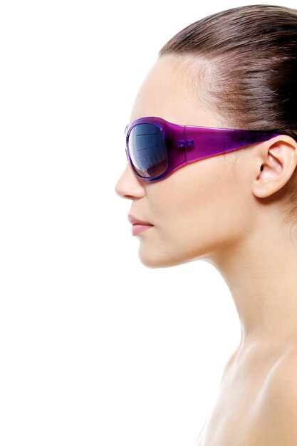 Retrato de perfil de un rostro de mujer joven en gafas de sol violetas