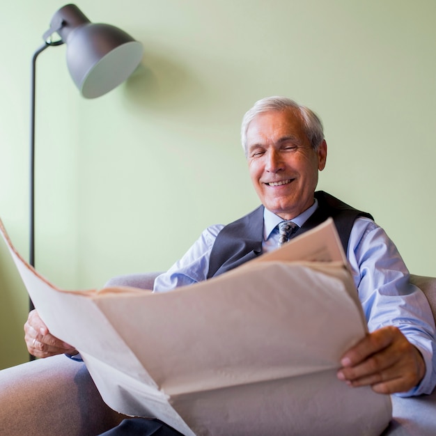 Retrato del periódico mayor sonriente de la lectura del hombre de negocios