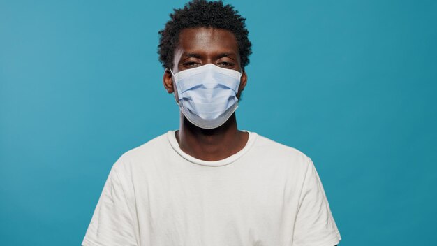 Retrato de una persona casual con mascarilla y mirando la cámara. Primer plano de un joven con máscara protectora contra la pandemia del coronavirus sobre un fondo aislado en el estudio.