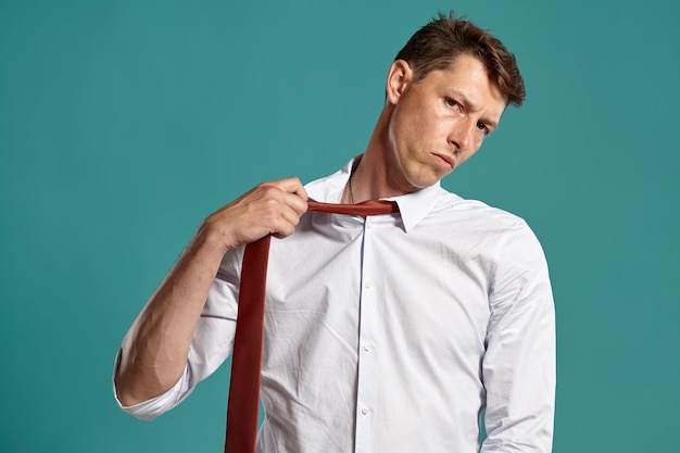 Foto gratuita retrato de una persona morena guapa con ojos marrones, vestida con una camisa blanca clásica y una corbata roja, que relaja. está posando en un estudio sobre un fondo azul. concepto de gesticulación