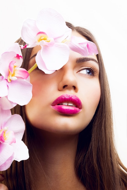 Retrato de primavera de belleza de dama tierna y seductora con flores rosas, labios grandes y maquillaje natural