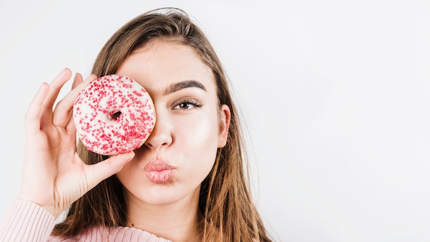 Retrato del primer de los labios que ponen mala cara de la mujer joven y de los ojos de la cubierta con los anillos de espuma aislados en el contexto blanco